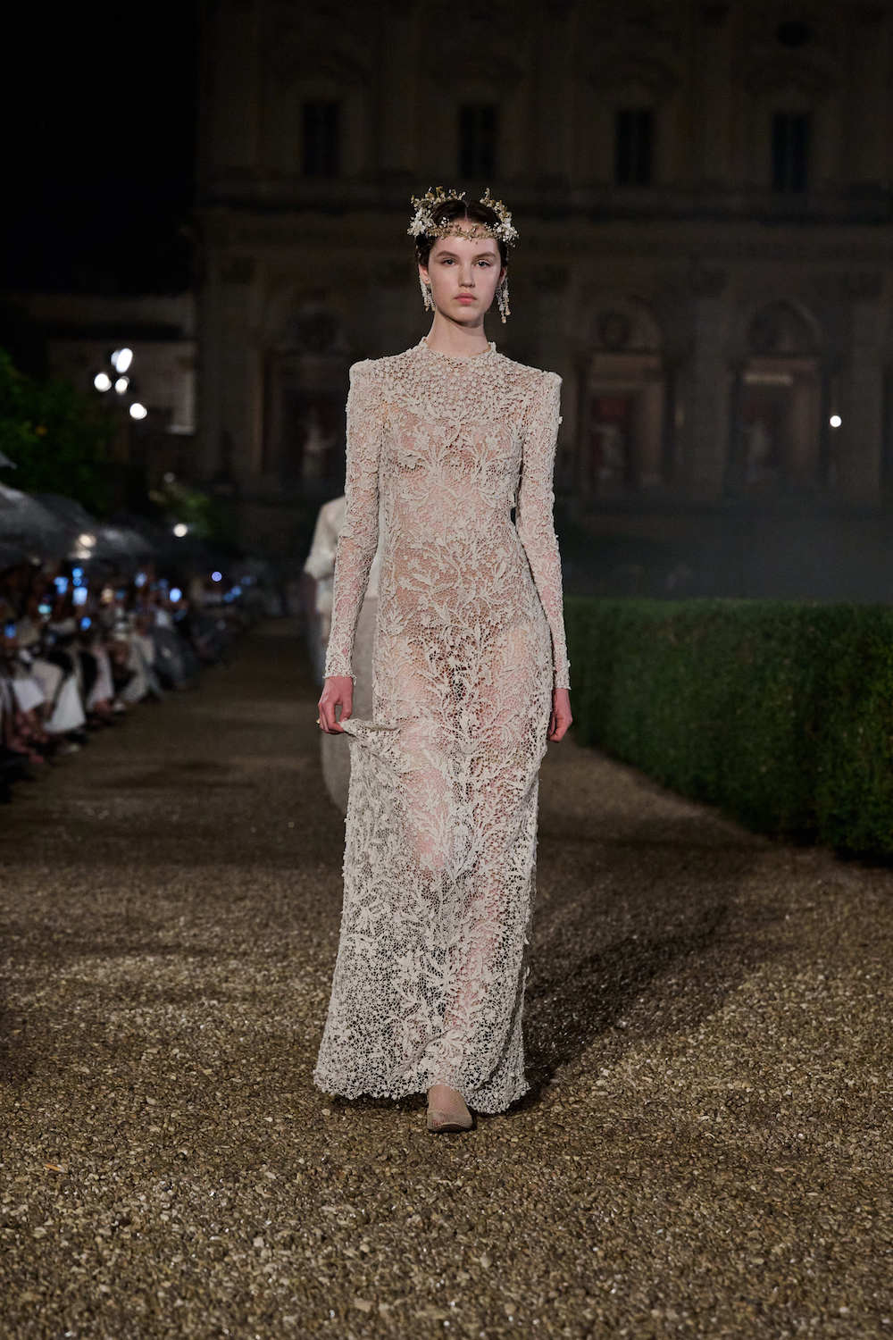 Modelka w koronkowej sukience na lato, idealnej na ślub, prezentuje się na eleganckim wybiegu.