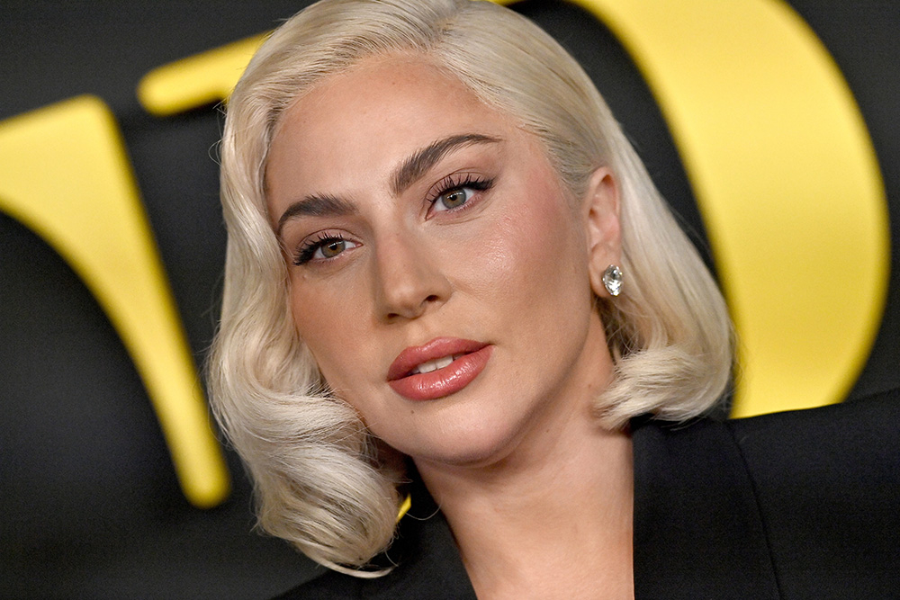 Lady Gaga w eleganckim stroju, z krótkimi, jasnymi włosami i subtelnym makijażem, patrzy w obiektyw.
