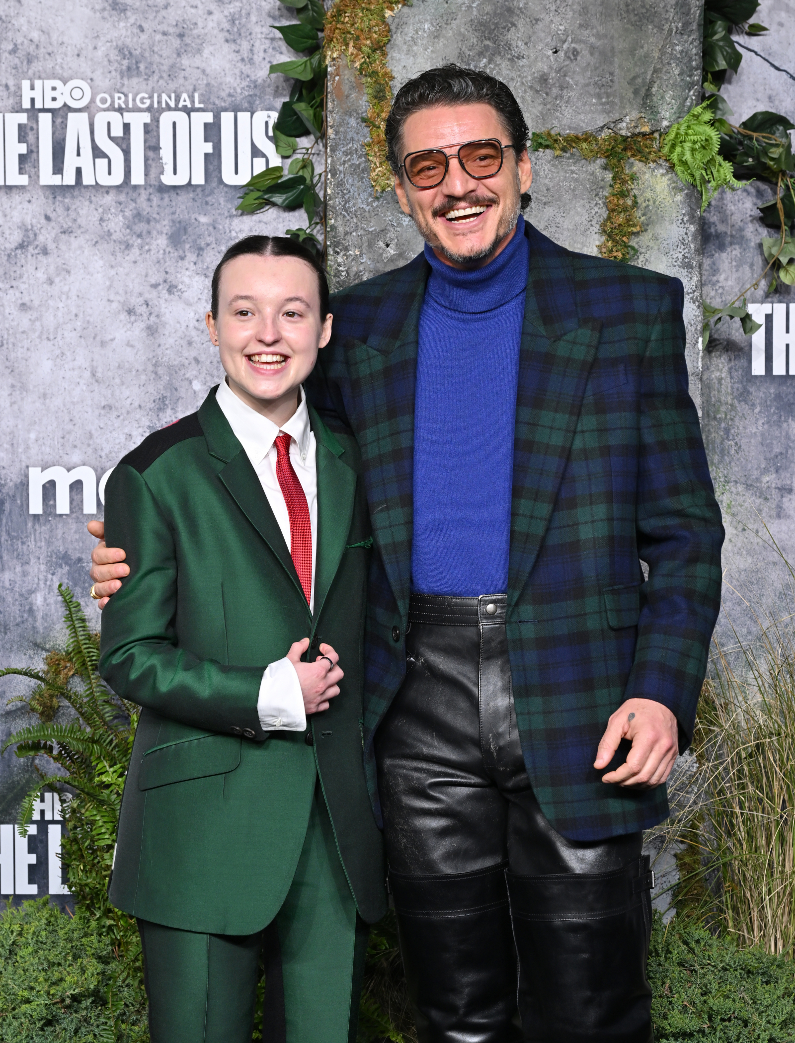 Bella Ramsey i Pedro Pascal uśmiechają się na czerwonym dywanie, pozując razem w eleganckich strojach.
