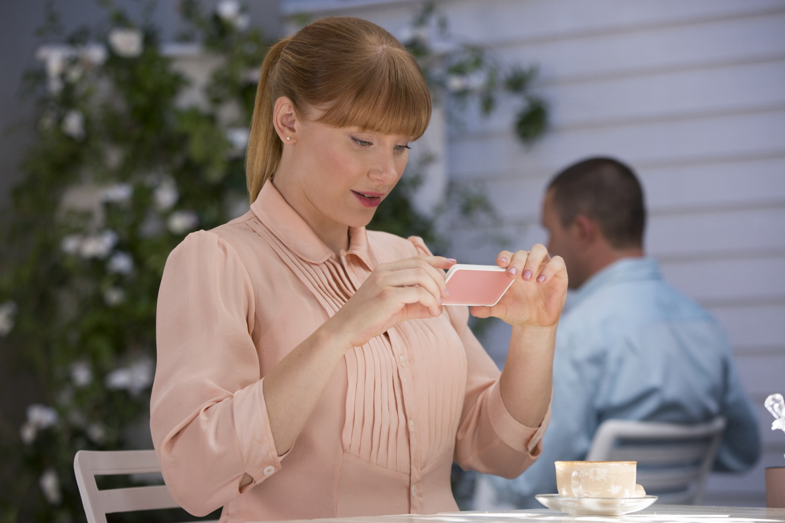 Bryce Dallas Howard w serialu Netflix „Czarne lustro”, robi zdjęcie telefonem w kawiarni.