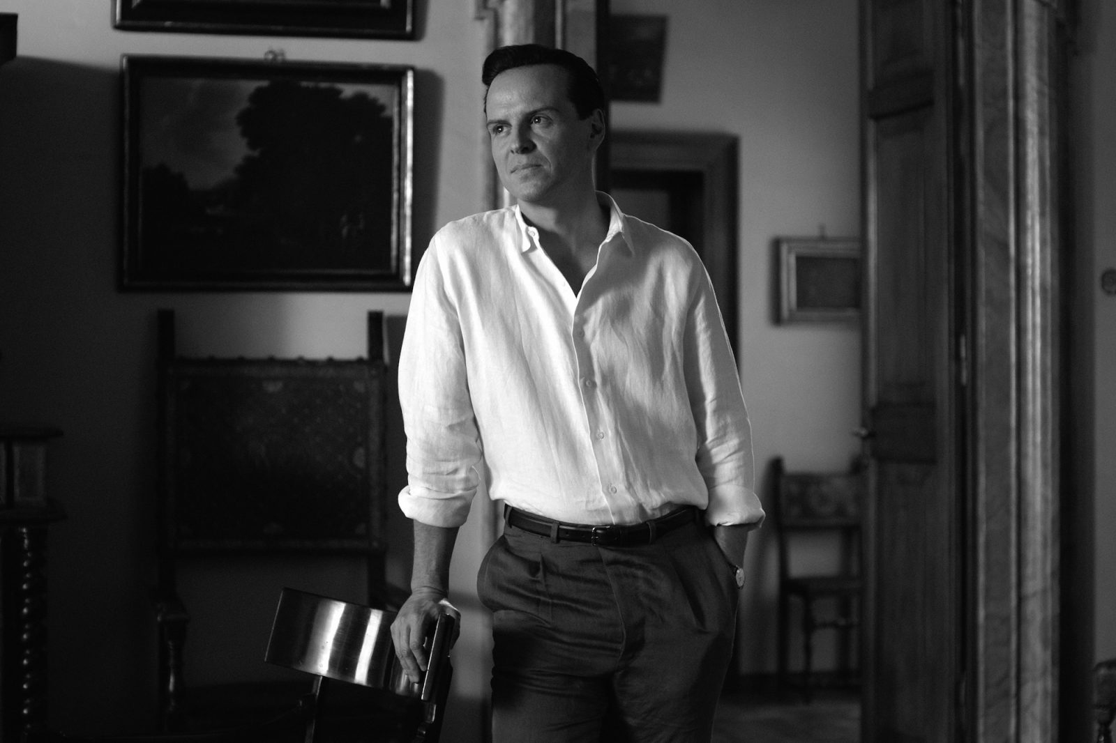 Andrew Scott w białej koszuli, stojący w stylowym wnętrzu. Aktor znany z roli w serialu Netflix „Ripley”.