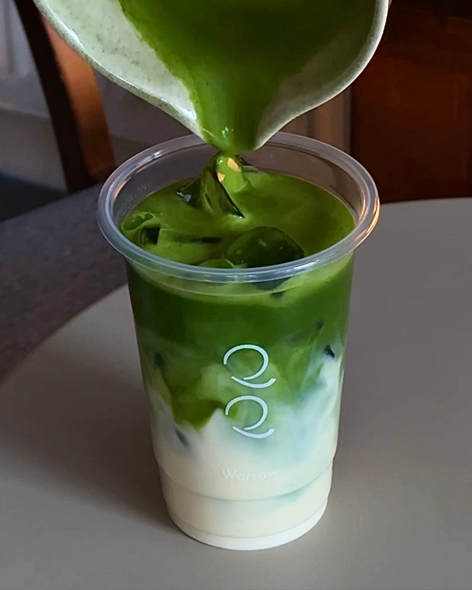 Miska z napojem matcha w kawiarni QQ, z widokiem na warstwy zielonej herbaty i mleka.
