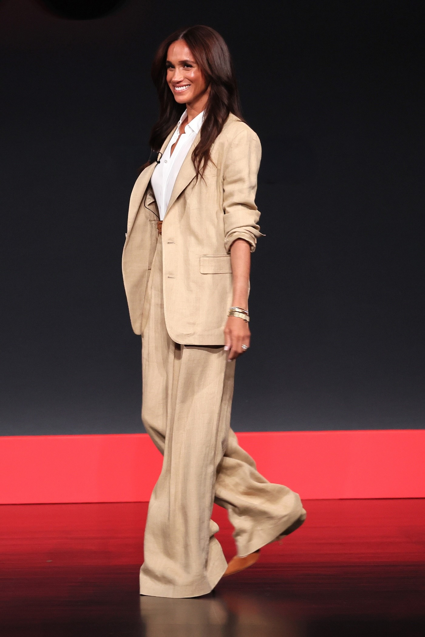 Meghan Markle podczas wystąpienia na Time100 Summit ma na sobie lniany garnitur marki Ralph Lauren z lekko oversize’ową marynarką i spodniami typu palazzo, białą koszulę i jasnobrązowe zamszowe czółenka.