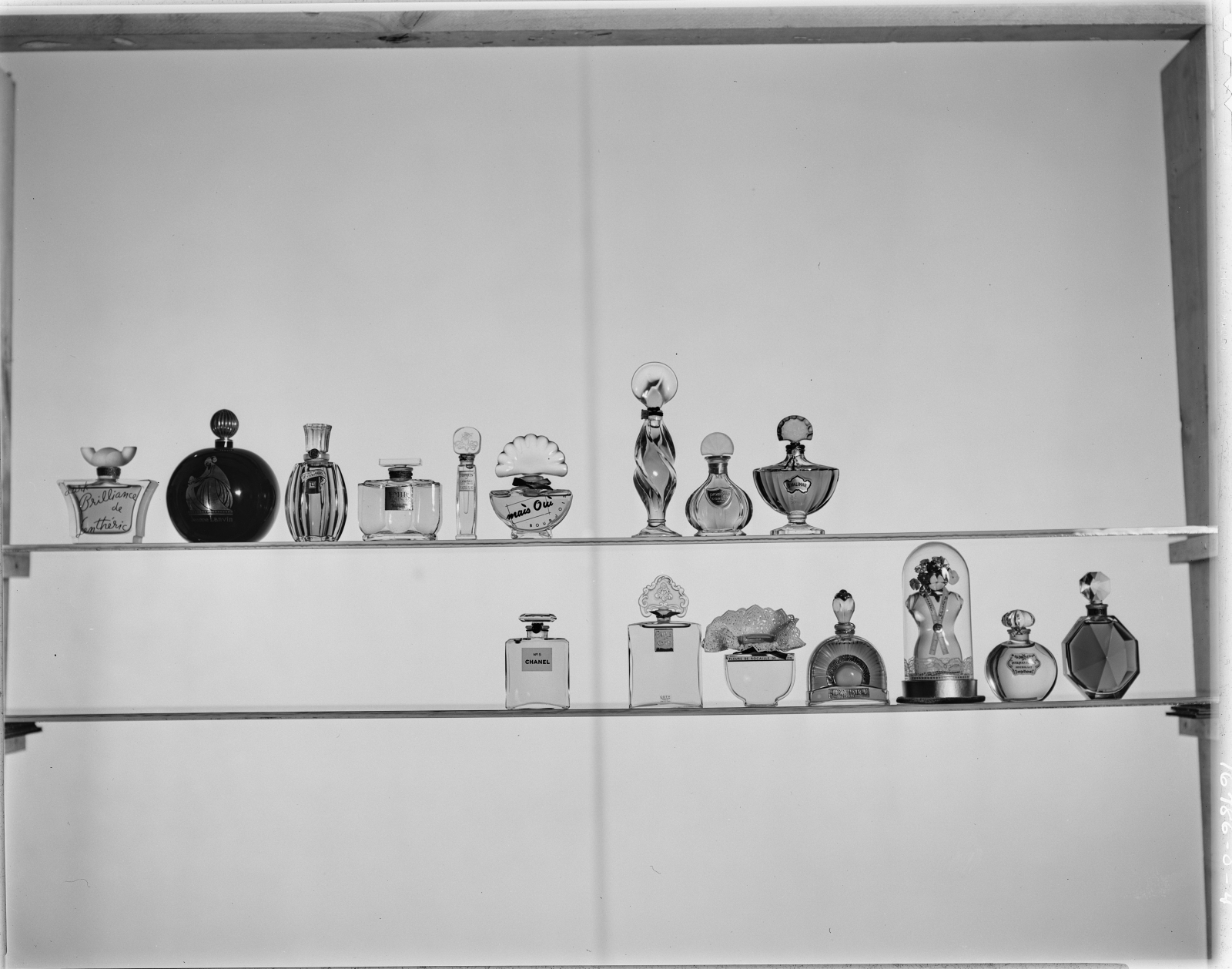 Kultowe perfumy w historycznych flakonach na półce, ukazujące różnorodność stylów i designu.