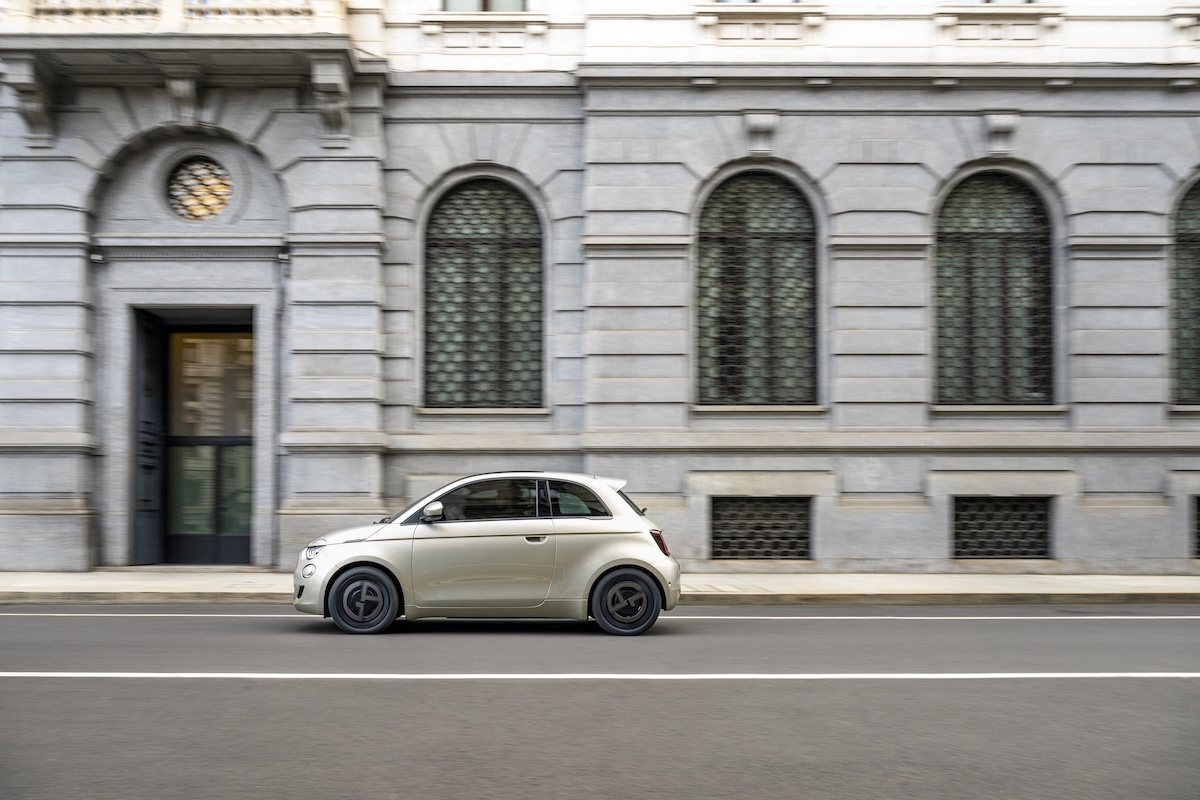 Samochód Fiat 500e Giorgio Armani w kolorze szarobeżowym jedzie po ulicy Mediolanu.