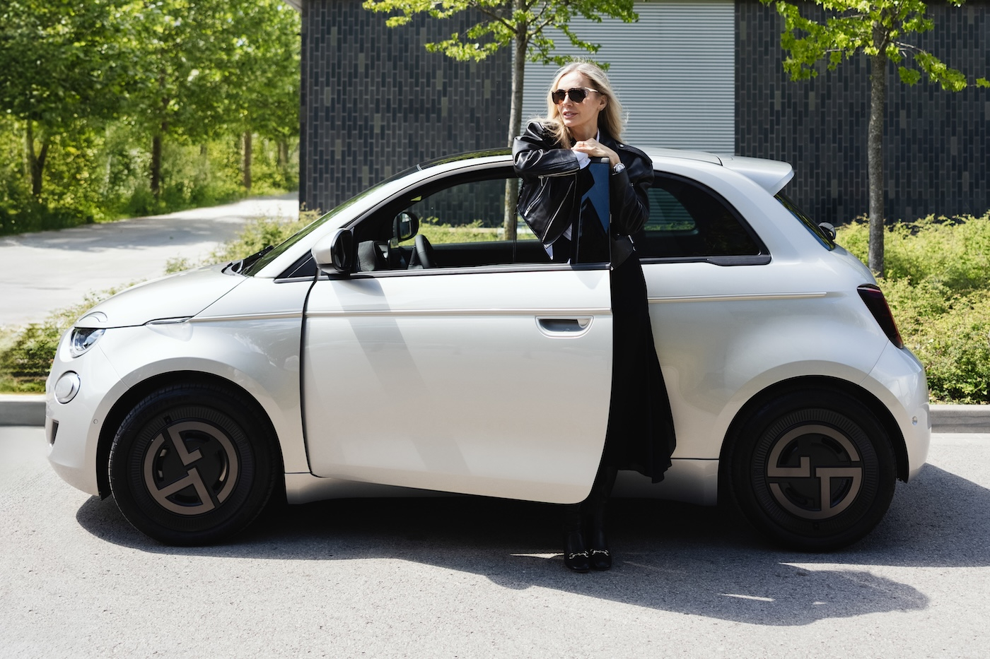 Agnieszka Woźniak-Starak pozuje do zdjęcia przy otwartych drzwiach samochodu Fiat 500e Giorgio Armani.