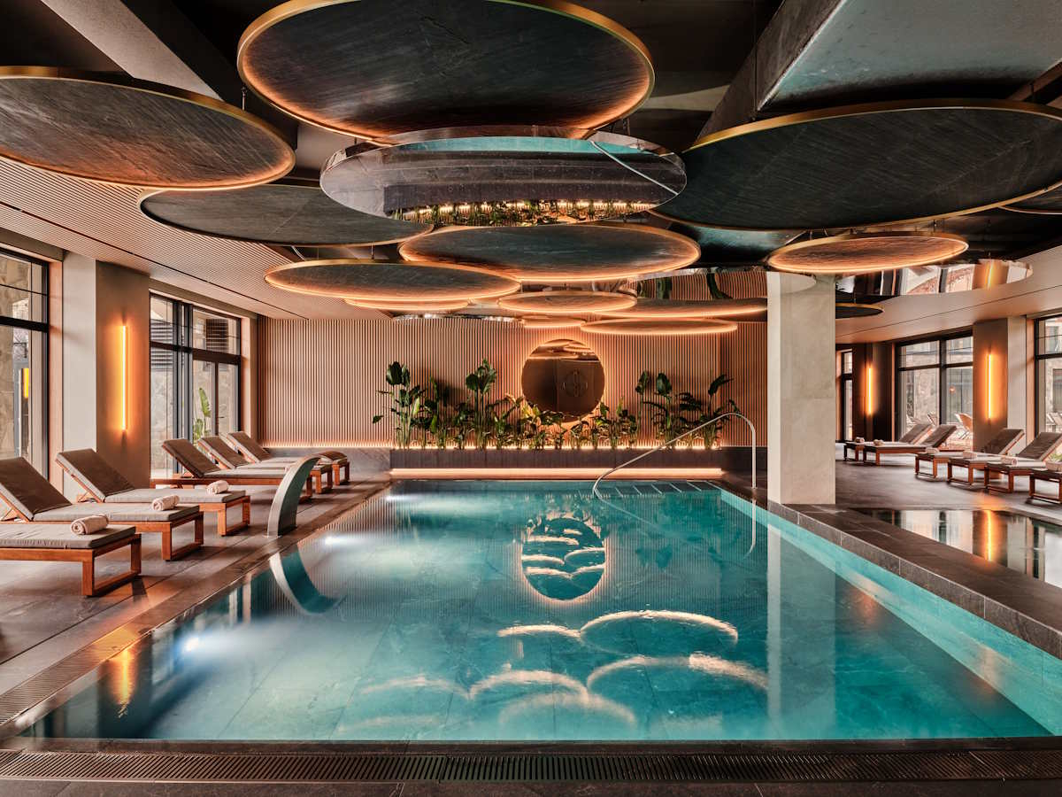 Nowoczesny spa z basenem, stylowymi leżakami i eleganckim oświetleniem, w otoczeniu roślinności w Mövenpick Resort & Spa Karpacz.