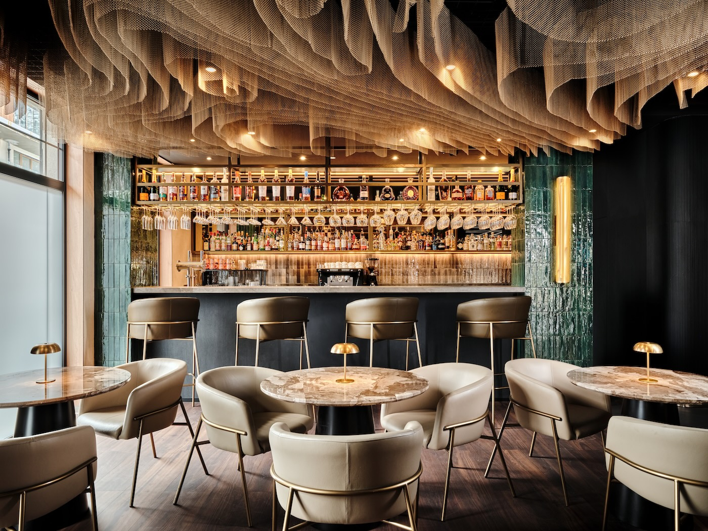 Elegancka przestrzeń baru z podświetloną ladą, architektonicznym sufitem i luksusowymi fotelami przy stolikach w Mövenpick Resort & Spa Karpacz.
