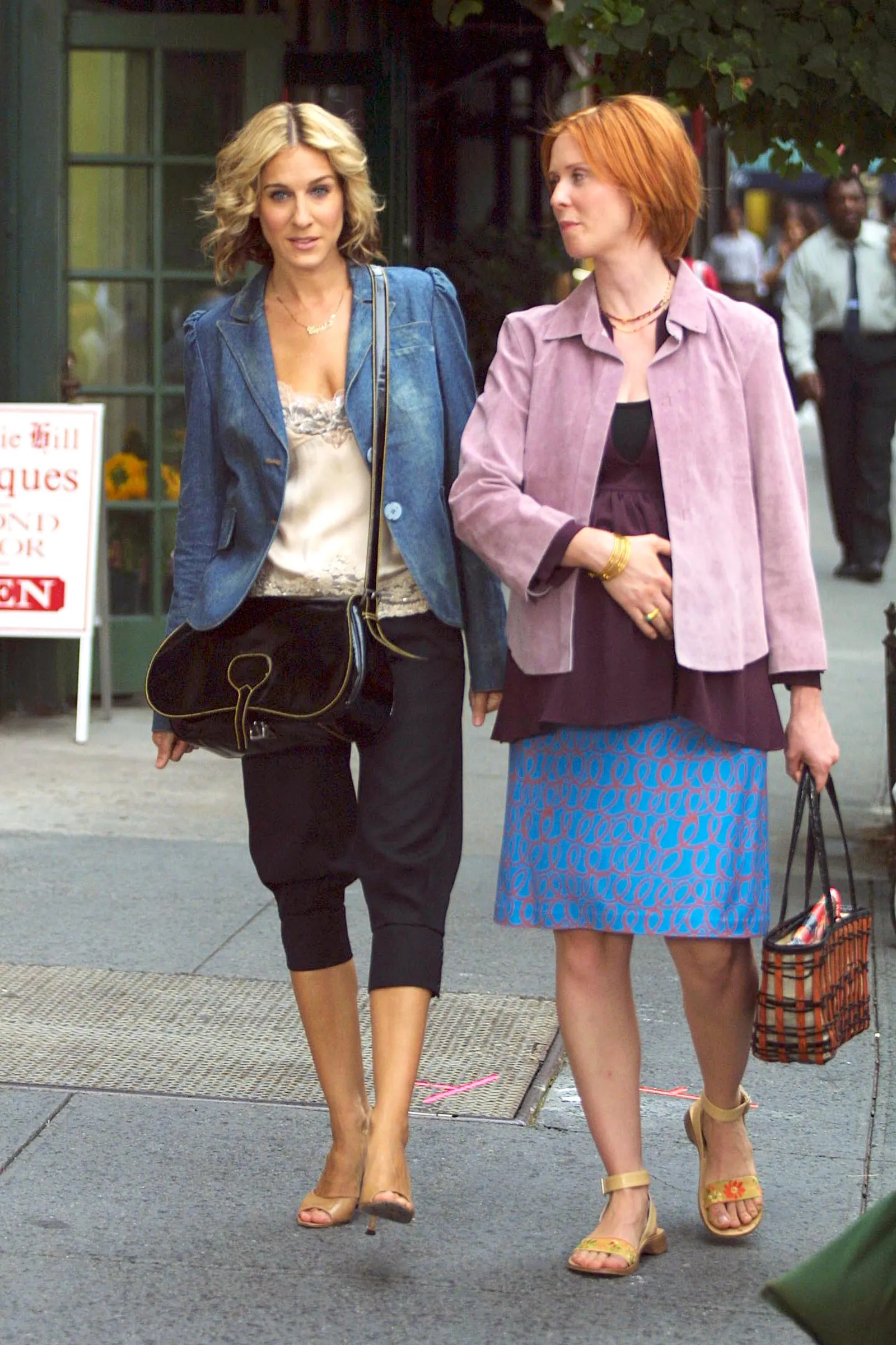 Sarah Jessica Parker jako Carrie Bradshaw i Cynthia Nixon jako Miranda Hobbes spacerują po mieście, ubrane w stylowe stroje.